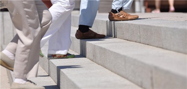 Mehrere ältere Personen steigen eine Treppe hinauf. Es sind nur ihre Beine und Füße zu sehen.