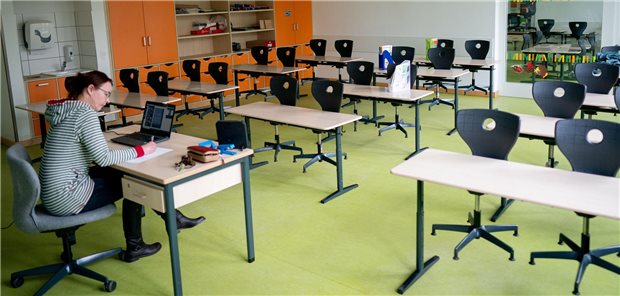 Gute Bildung als Puffer in der Corona-Pandemie Schulen im Shutdown: Eine Lehrerin sitzt in ihrem leeren Klassenzimmer vor
einem Laptop und hält eine Videokonferenz mit ihren Schülern.