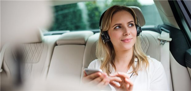 Reisekrankheit: Die richtige Musik kann helfen Eine Frau sitzt auf dem Rücksitz eines Autos und hört Musik.