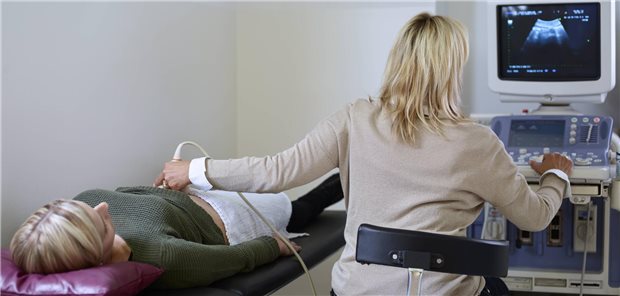 Frau sonografiert Patientin.