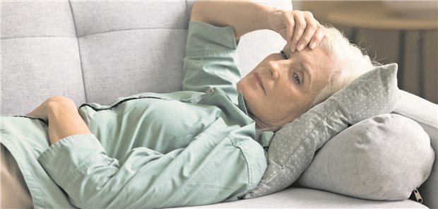 Eine Frau liegt auf dem Sofa und sieht erschöpft aus. 