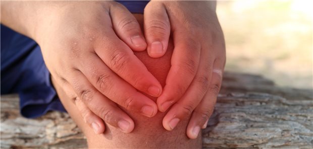 Mann fasst sich ans Knie