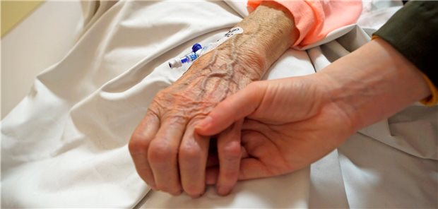 jüngere Person hält die Hand einer Älteren, der ein Zugang gelegt wurde.