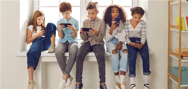 Kinder verschiedener Nationalitäten spielen Online-Spiele oder lesen soziale Netzwerke auf Mobiltelefonen.