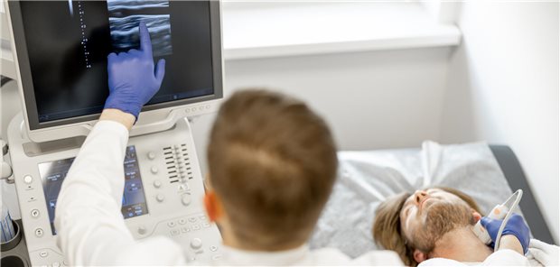 Ein Arzt untersucht die Carotis eines Patienten mittels Ultraschall.