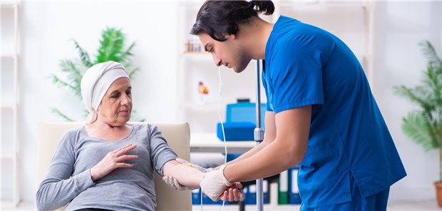 Junger Arzt versorgt ältere Krebspatientin.