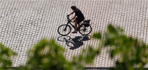 Ein Mann fährt mit dem Rad über eine gepflasterte Straße.
