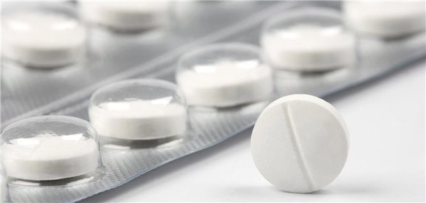 Eine weiße Tablette steht auf der Kante. dahinter liegt eine Blisterverpackung. 