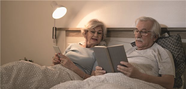 Blutdruckmessung eines Mannes der auf seinem Bett liegt und schläft.